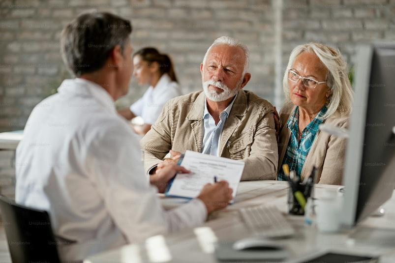 A professional explaining documentation of Medicare supplement insurance in Fresno to an elder couple