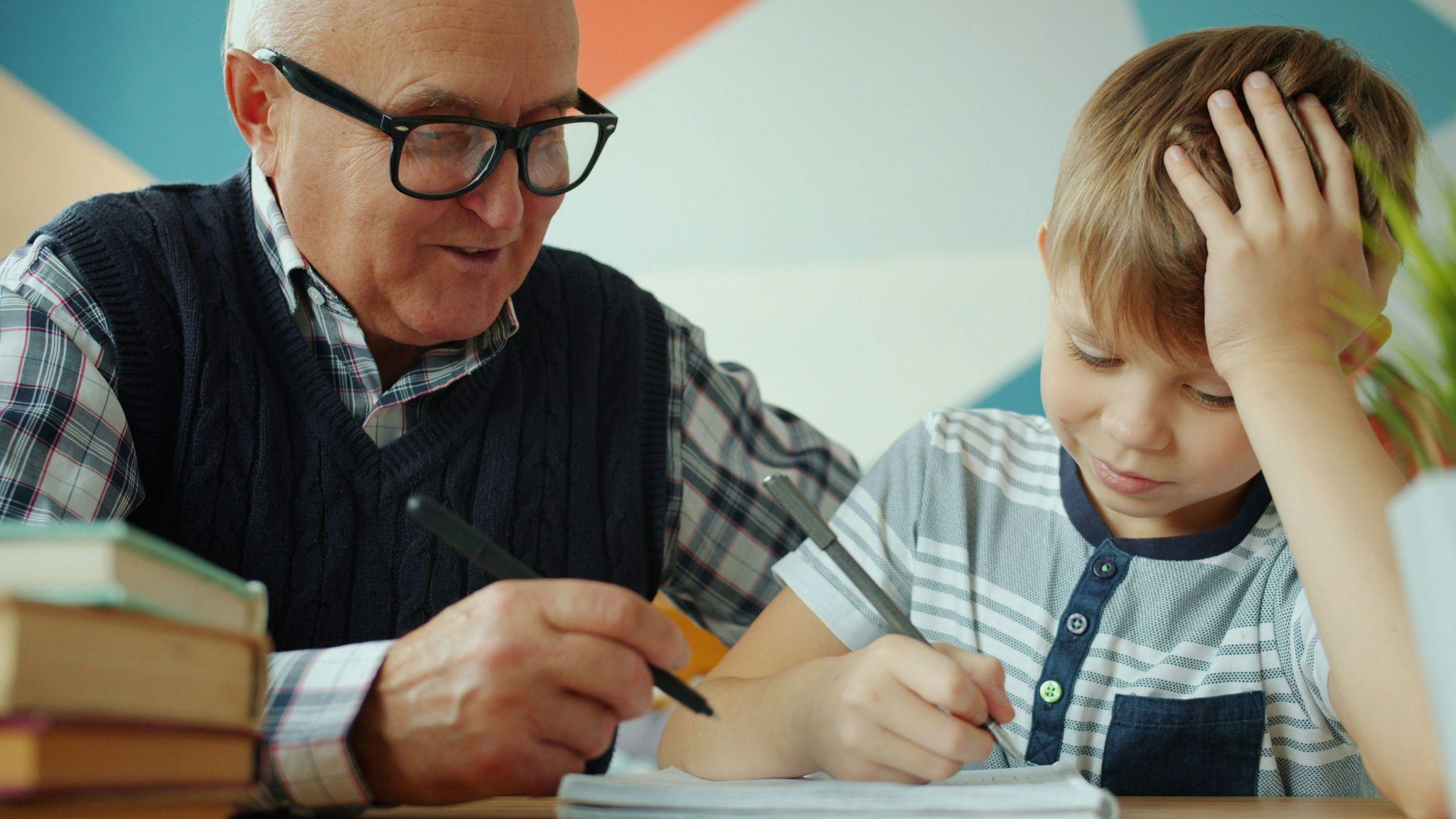 A grandfather helps a young child with schoolwork, illustrating the value of accessible vision insurance in Fresno.