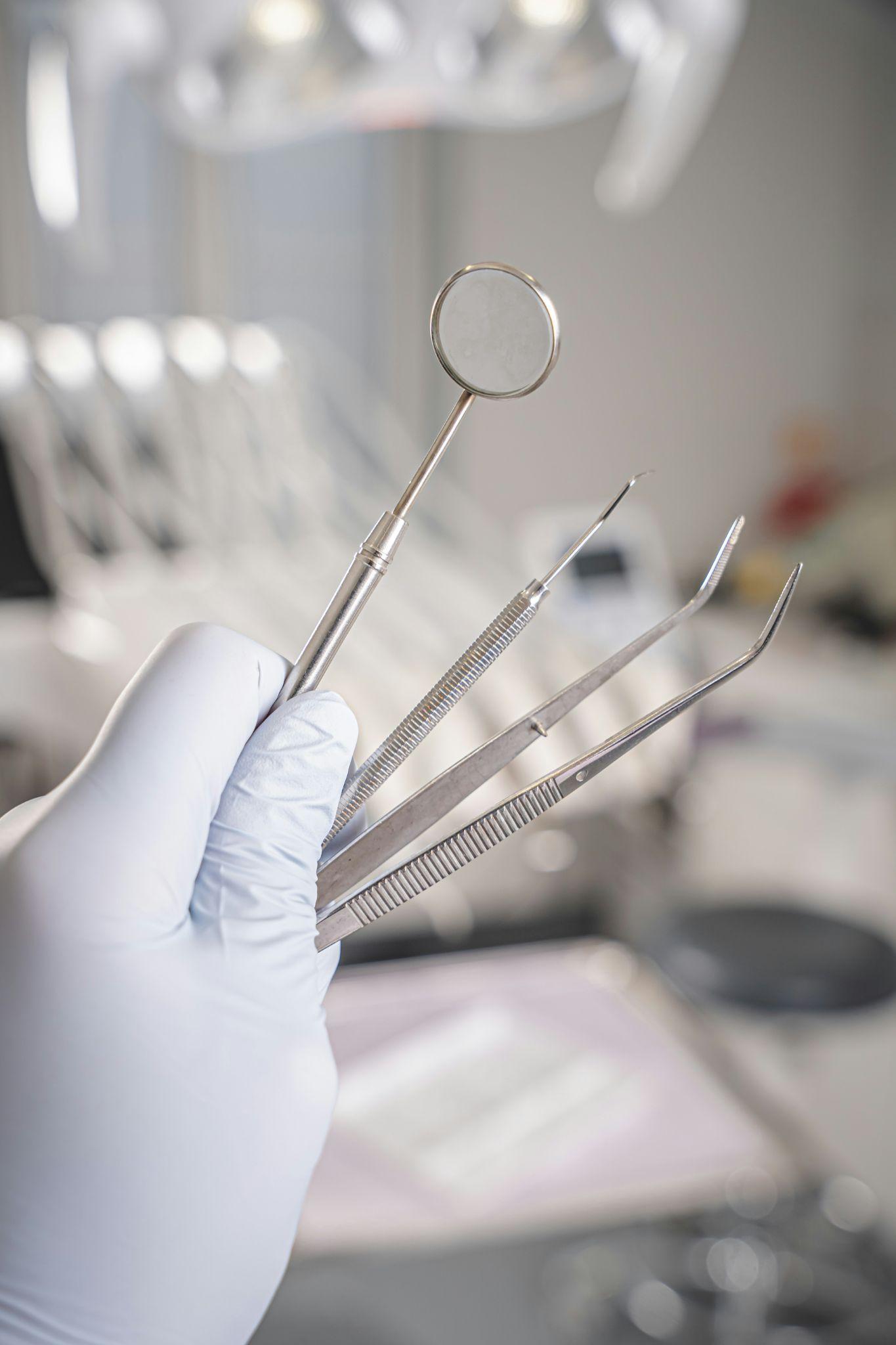 A gloved hand holding dental examination instruments highlights procedures supported by senior dental insurance in Fresno.