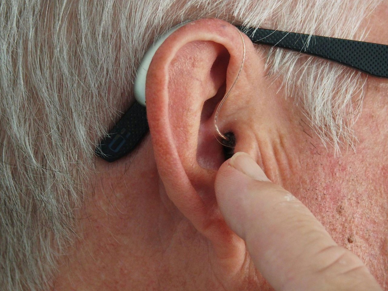 Senior wearing a hearing aid with hearing insurance in California.