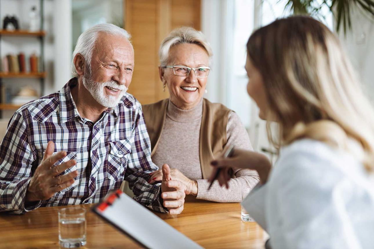 Senior couple discussing hearing aid options and senior hearing insurance in California with a professional.