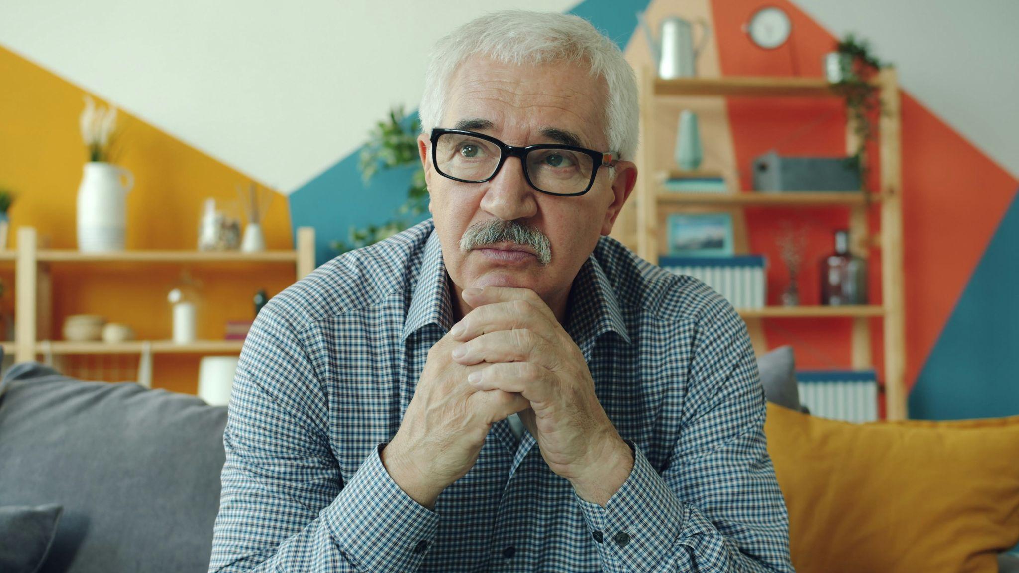 An older man wearing glasses considering vision insurance plans in California.